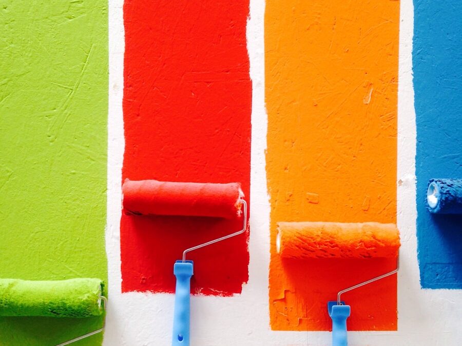 Painting a room color choices - four orange, green, blue, and red paint rollers